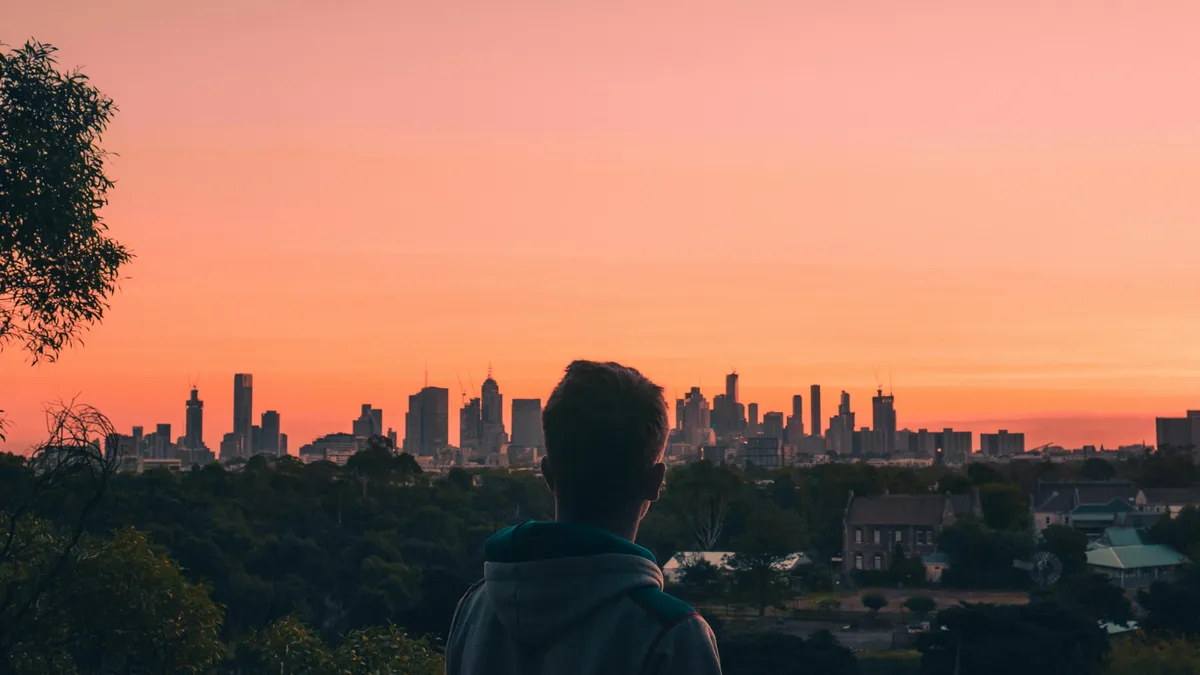 Against a kaleidoscope of oranges, yellows, and pinks, a solitary figure stands out in silhouette, admiring the majestic…