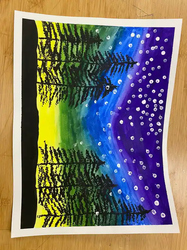 A child's painting on paper shows two black pine trees against a vibrant gradient sky transitioning from yellow to green to…