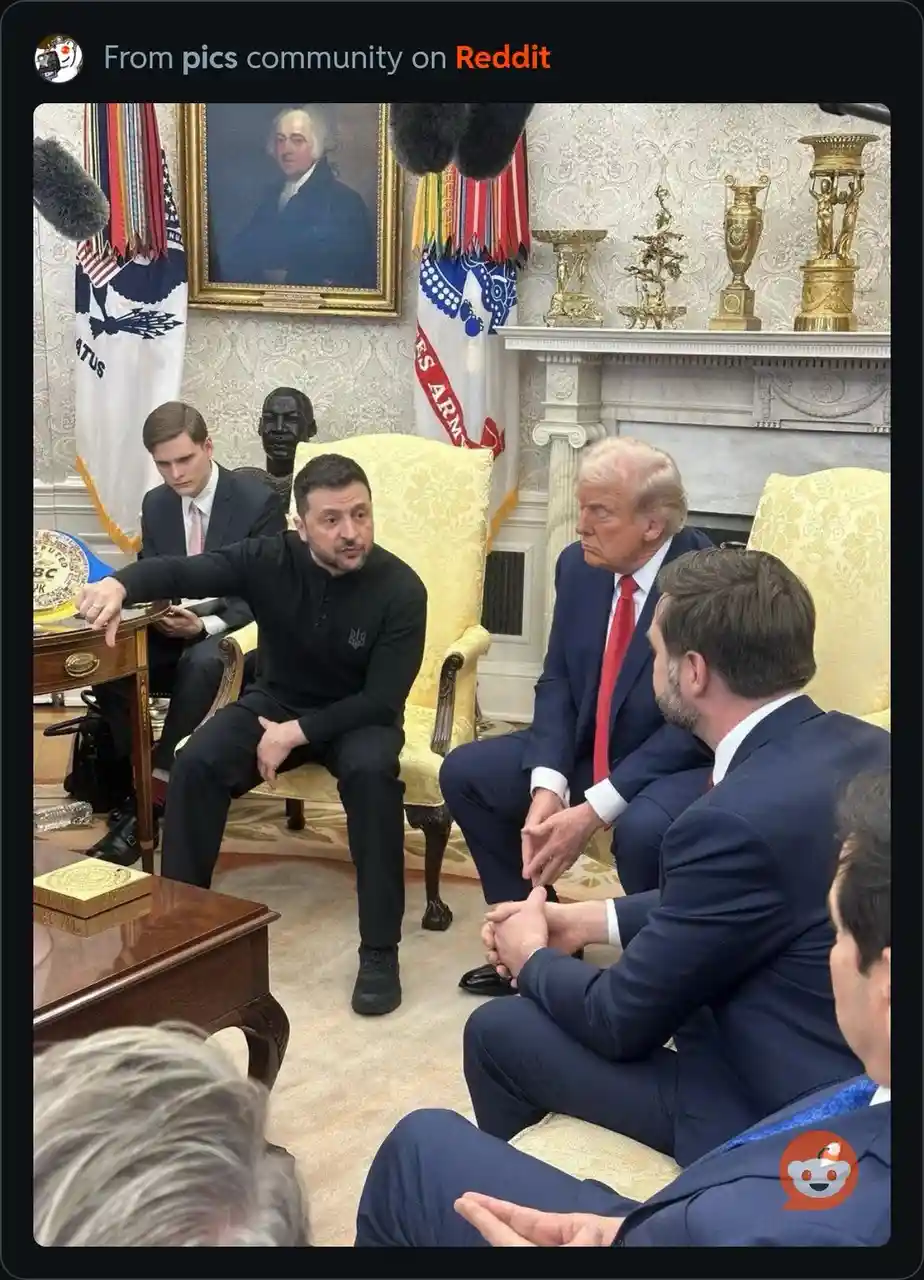 A photo shows Ukrainian President Volodymyr Zelenskyy seated in a formal room, gesturing emphatically toward a table with a…